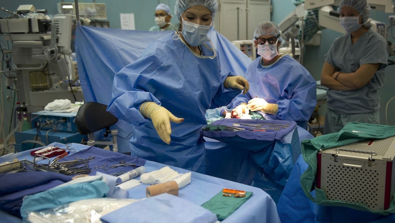 pracowniczka medyczna sięgająca po narzędzie w czasie operacji