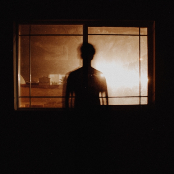 osoba w ciemnym pomieszczeniu oświetlana przez okno