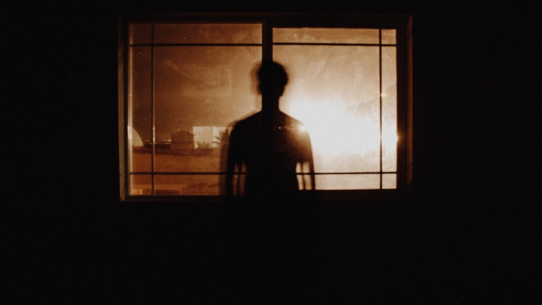 osoba w ciemnym pomieszczeniu oświetlana przez okno